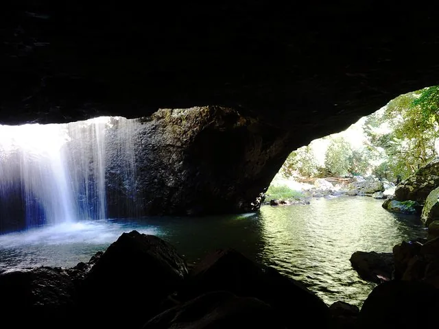 A waterfall pouring into a dark cave pool at Natural Bridge, Springbrook National Park