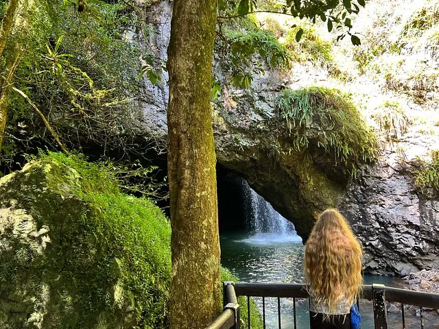 Woman looking at a waterfall in a cave at Springbrook National Park
