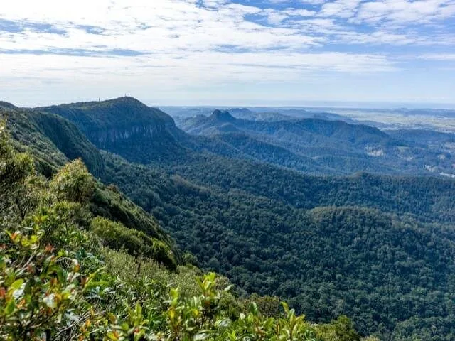 Panoramic view of lush, forested mountain ridges under a partly cloudy sky.