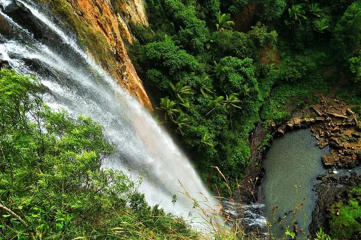 A high waterfall cascading down a cliff face towards a deep pool