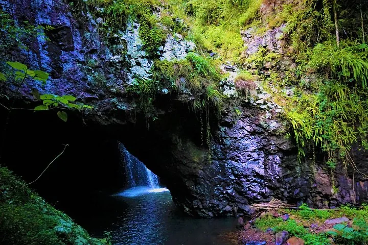 A view from outside looking into the Natural Bridge rock arch and waterfall